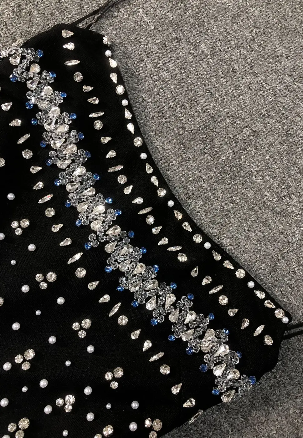 Close-up of rhinestone embellishment on black strapless bandage mini dress