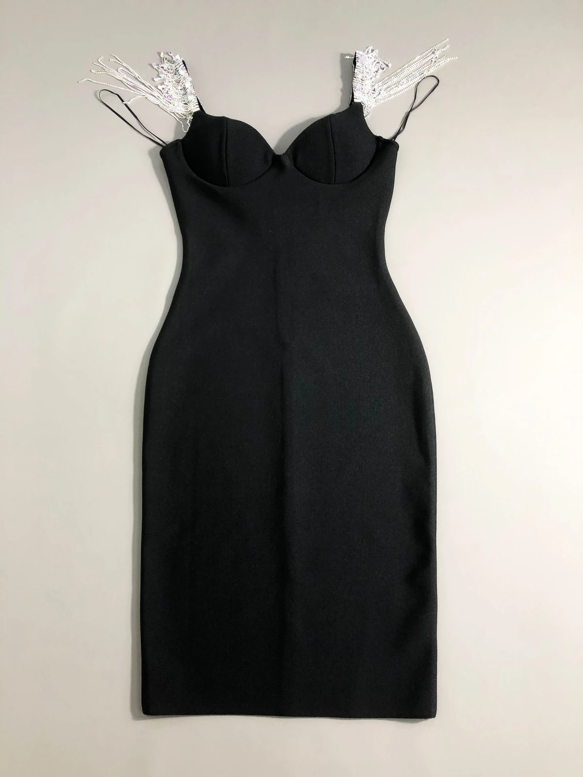 Flat lay of black V neck bandage dress with rhinestone fringe chain straps