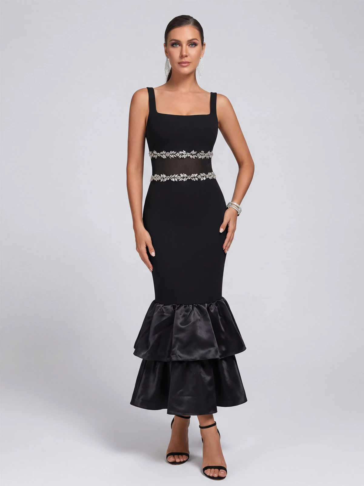 Model wearing black square neck bandage maxi dress with rhinestone mesh waist and tiered ruffle hem, front view