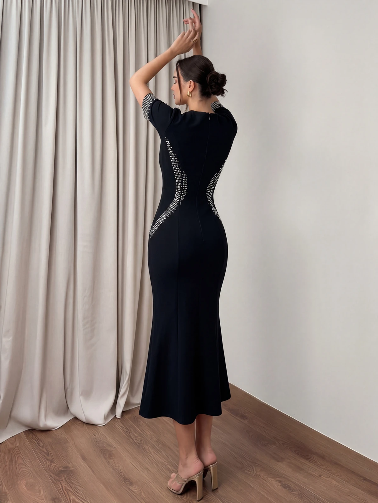 Back view of black short sleeve bandage dress with curved rhinestone panels