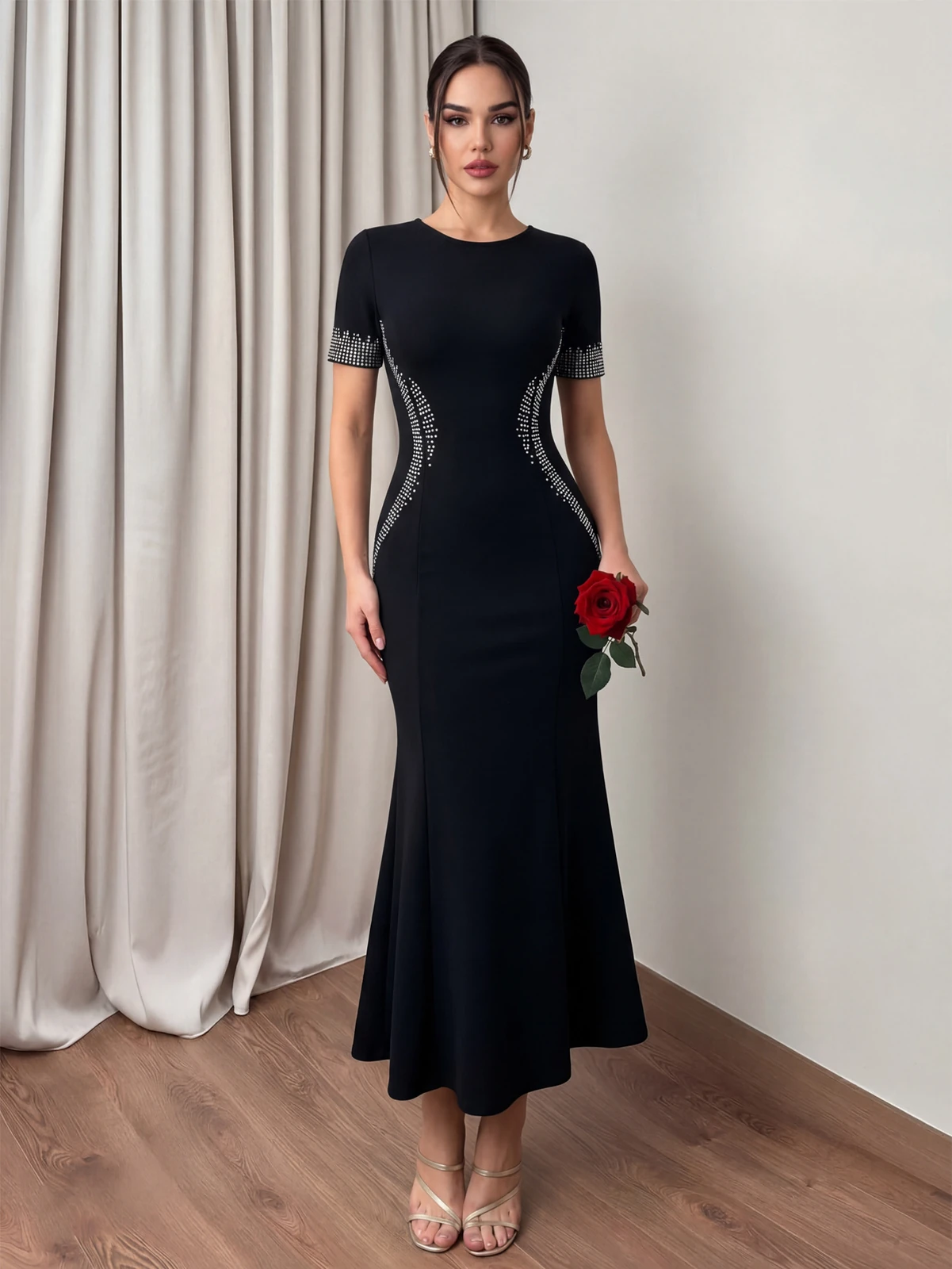Model wearing black short sleeve bodycon bandage dress with curved rhinestone side panels and mermaid hem, front view