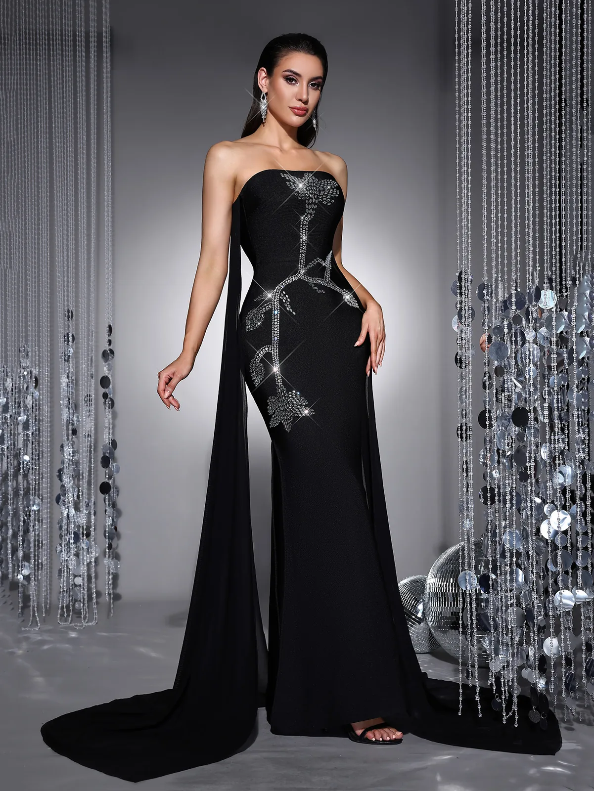 Model in black strapless rhinestone bandage maxi gown, angled view