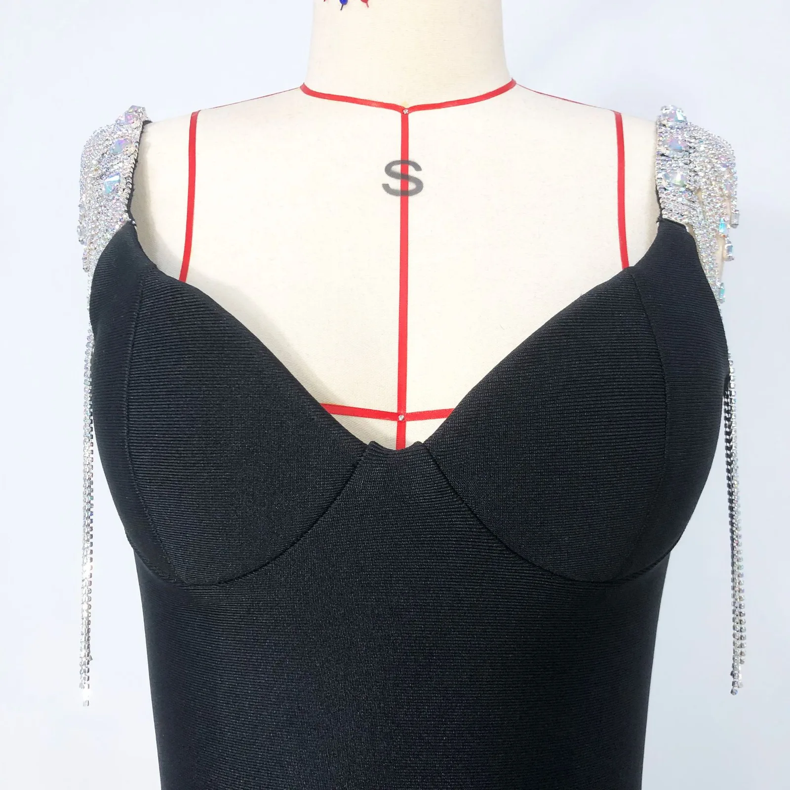 Close-up real photo of the V neck bodice and rhinestone fringe straps on black bandage dress