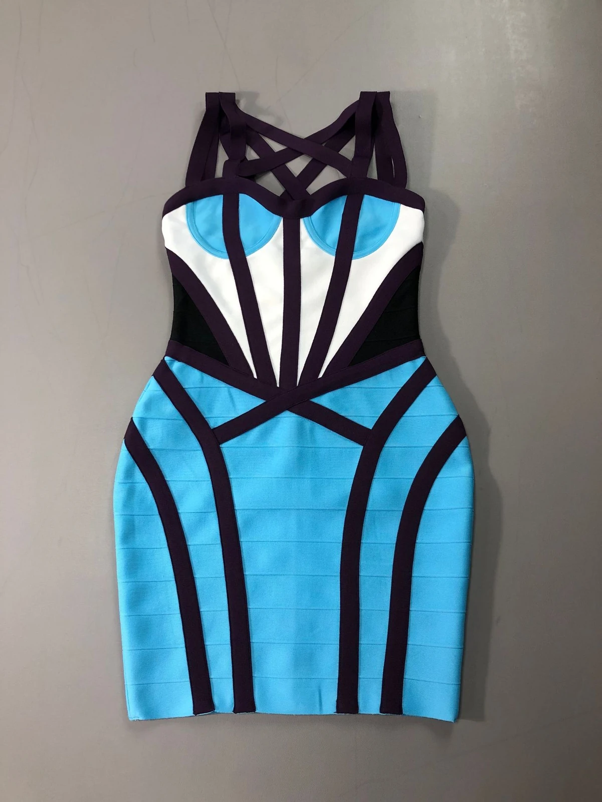 Flat lay of blue, white and purple colour block strappy bandage mini dress