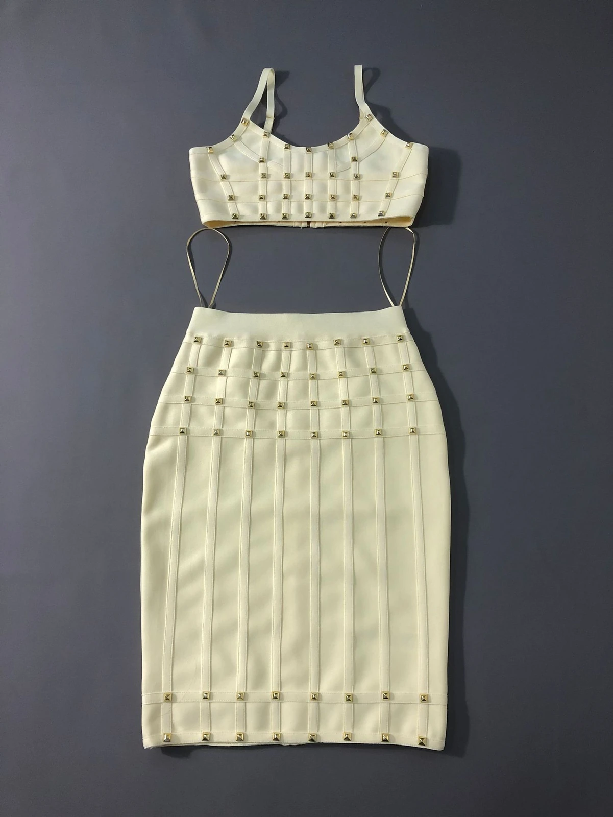 Flat lay of light yellow studded cami crop top and bandage pencil skirt two piece set