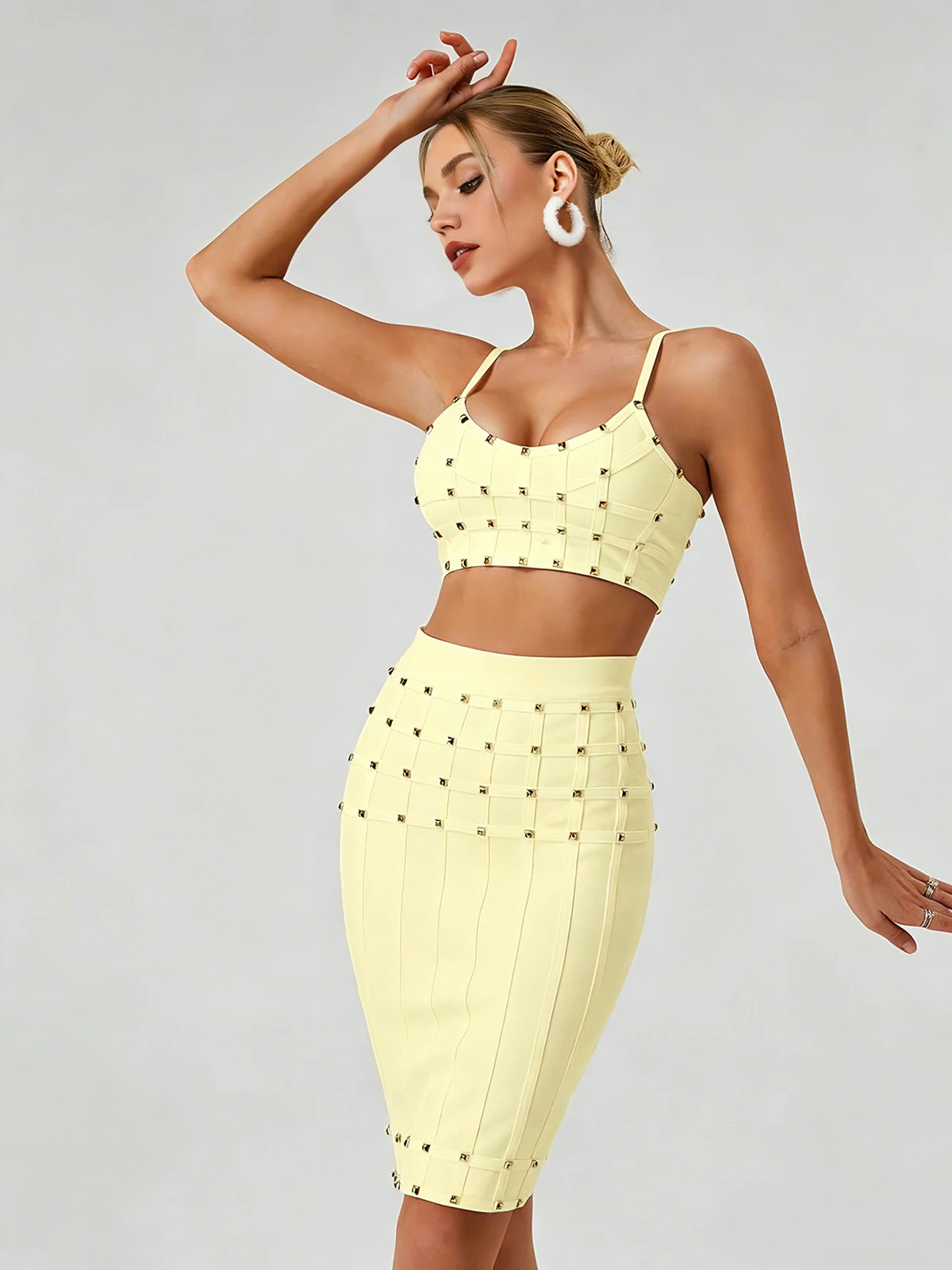 Model posing in light yellow studded cami crop top and bandage skirt set