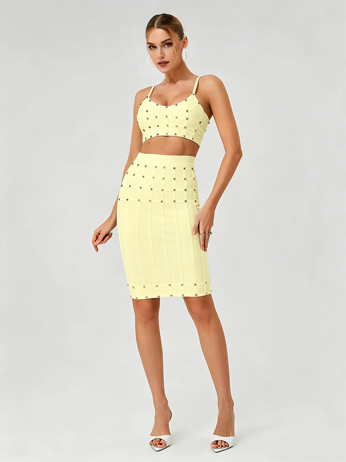 Model wearing light yellow studded cami crop top and bandage pencil skirt two-piece set, front view