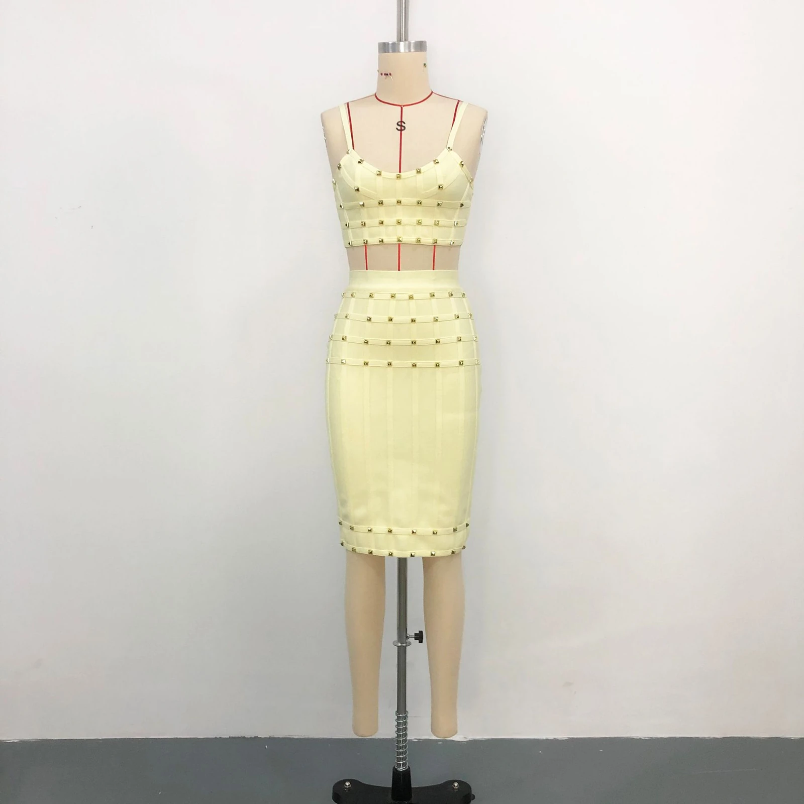 Real photo of light yellow studded cami crop top and bandage skirt set on a mannequin