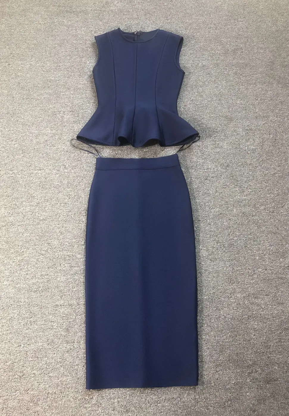 Flat lay of navy sleeveless peplum top and bandage pencil skirt two piece set