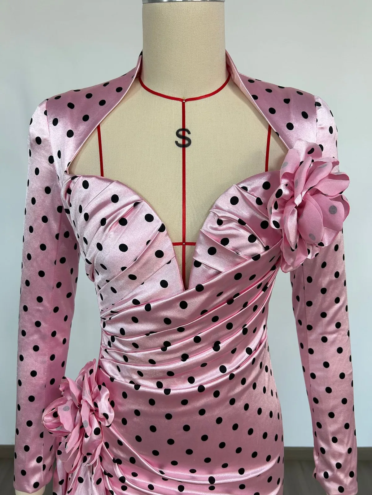 Close-up real photo of the deep V neckline and satin rose on pink polka dot mini dress