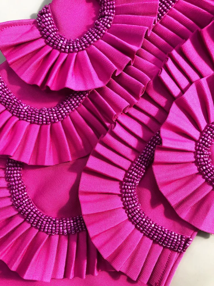 Close-up of the pleated ruffles and beading on rose red bandage maxi dress bodice