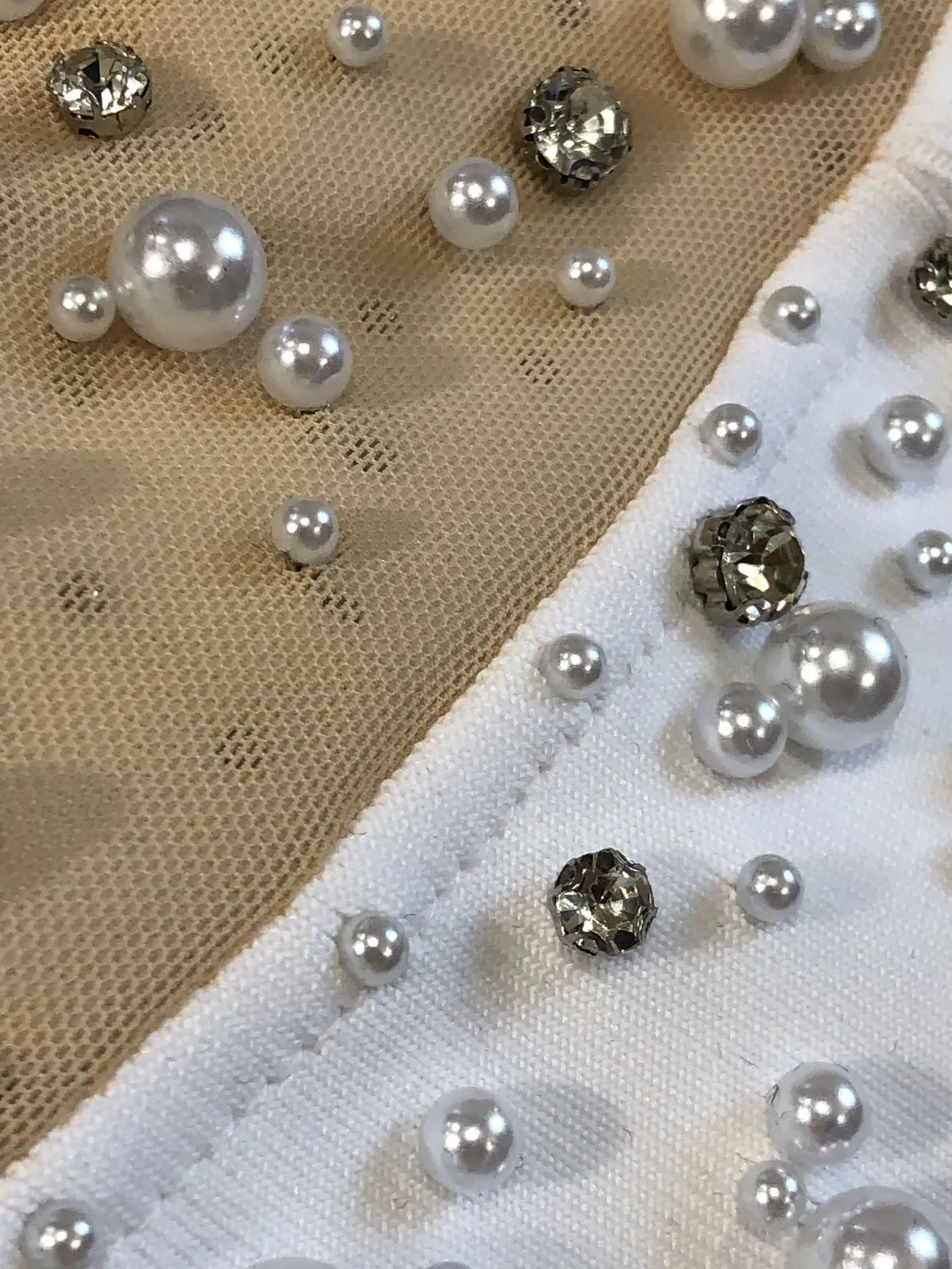Close-up of pearl and rhinestone beading on the sheer mesh panel of white bandage maxi dress
