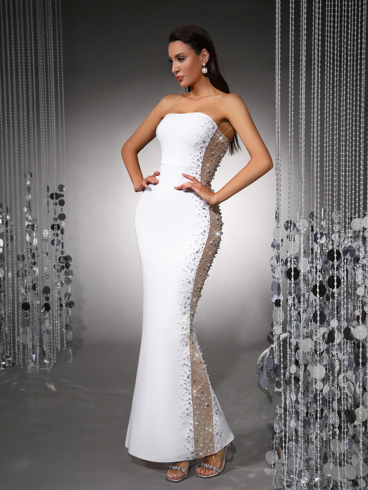 Model with hands on hips showing pearl beaded sheer mesh side panel of white bandage maxi dress