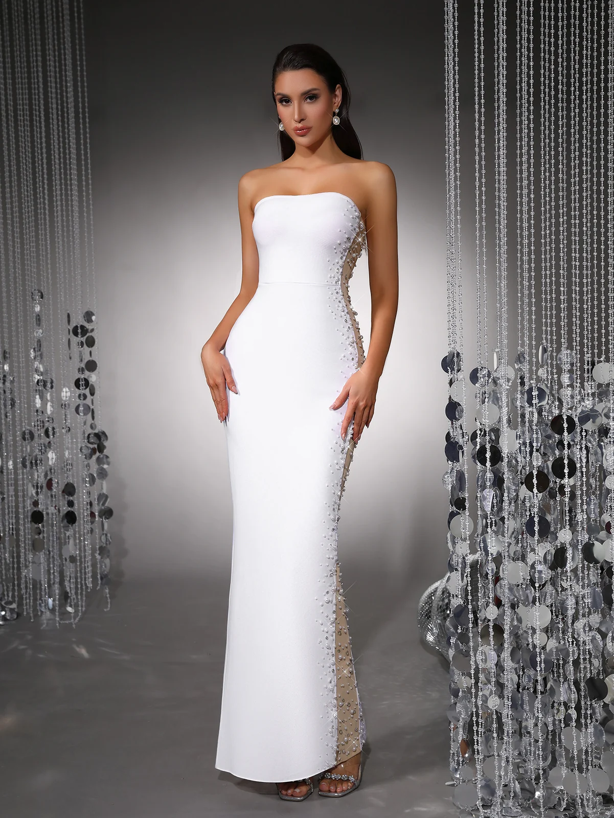 Model wearing white strapless bandage maxi dress with pearl beaded mesh side panels, front view