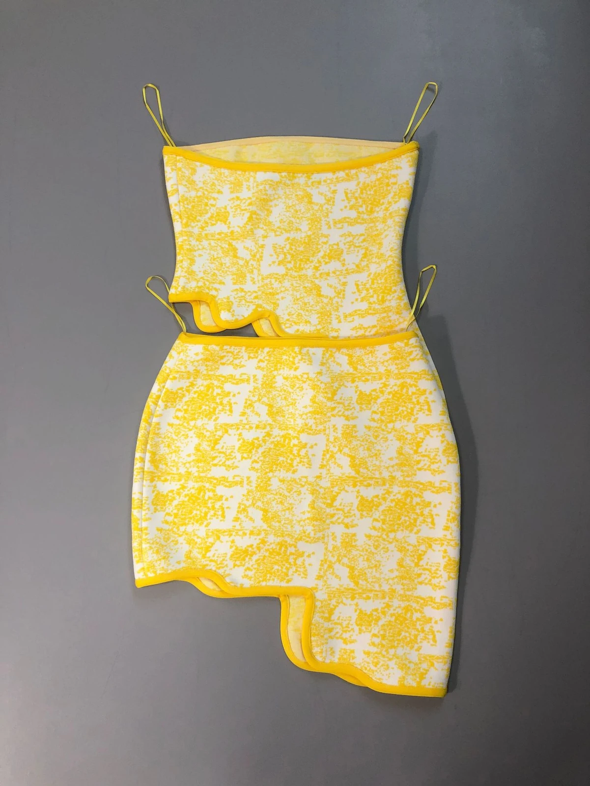 Flat lay of yellow and white jacquard strapless bandage crop top and asymmetric mini skirt