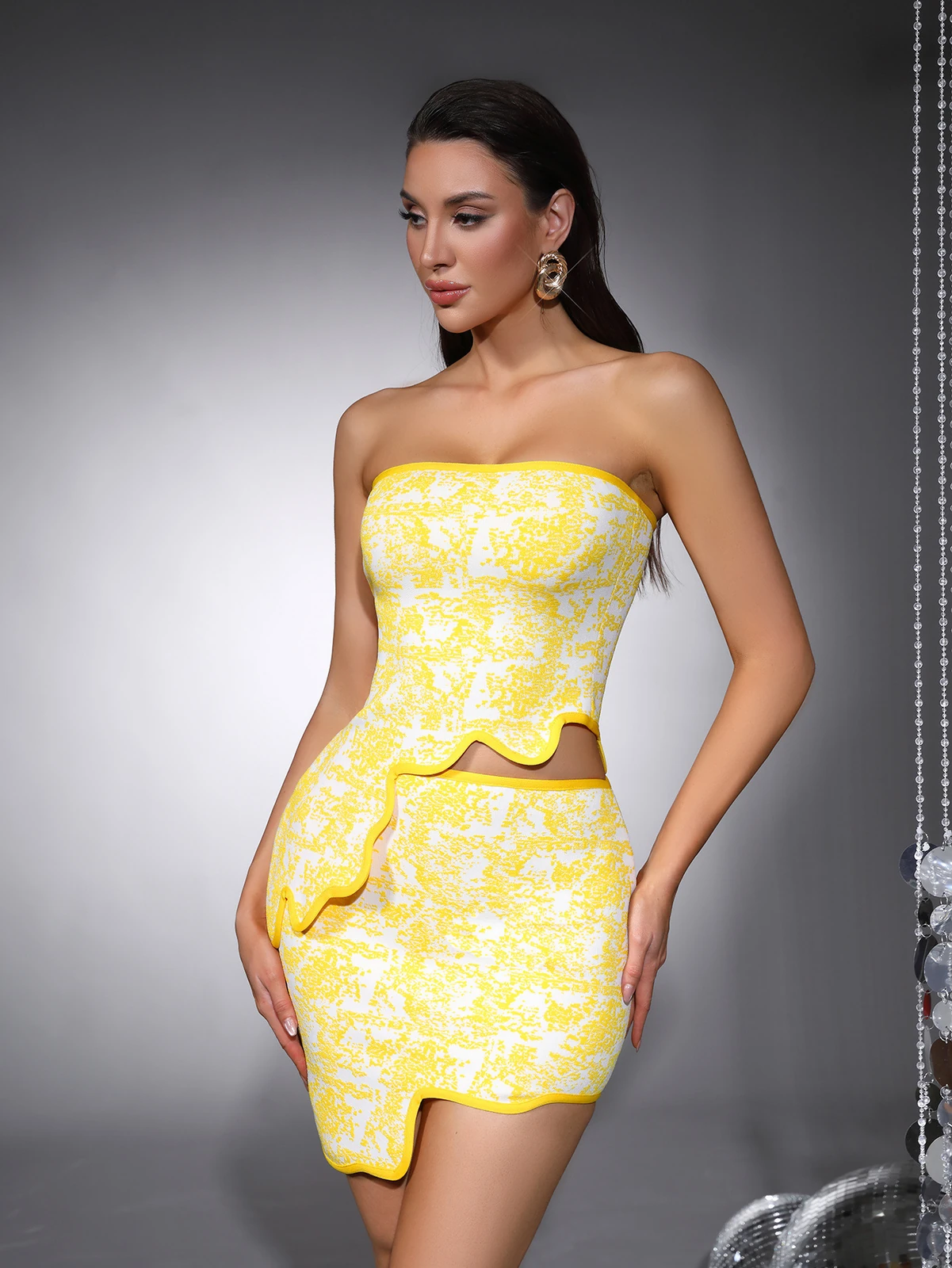 Model posing in yellow jacquard strapless bandage two-piece set with irregular hem